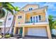 Charming yellow two-story home with balcony, turquoise door, brick driveway, and palm trees at 145 50Th St, Holmes Beach, FL 34217