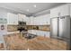 Close-up view of the kitchen island featuring granite countertops, white cabinets, and a stainless steel refrigerator at 145 50Th St, Holmes Beach, FL 34217