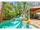 Backyard pool surrounded by tropical plants, outdoor grill, and covered outdoor seating at 145 50Th St, Holmes Beach, FL 34217