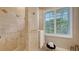 Bathroom with tile shower, stool, and window with white shutters at 1864 Goldenrod St, Sarasota, FL 34239