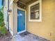 Blue front door with welcome mat on brick-paved porch, side light and manicured landscaping at 30073 Southwell Ln, Wesley Chapel, FL 33543