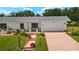 Charming home featuring brick pathway, garden beds, and attached two-car garage at 386 Club Manor Dr, Sun City Center, FL 33573