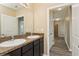 Bathroom featuring double sinks with dark cabinets, large mirror and view into the hallway at 4005 Willow Branch Pl, Palmetto, FL 34221