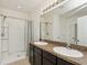 Well-lit bathroom with double sinks, granite countertop, and a walk-in shower with tiled floors at 4005 Willow Branch Pl, Palmetto, FL 34221