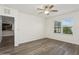 Bright bedroom features wood-look floors, ceiling fan, and an open doorway to the adjacent kitchen at 4005 Willow Branch Pl, Palmetto, FL 34221