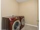 Modern laundry room featuring full-sized, front-loading washer and dryer in a beautiful red finish at 4005 Willow Branch Pl, Palmetto, FL 34221
