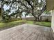 Large backyard with a wooden deck, green grass, and mature tree covered with Spanish moss at 4110 Longhorn Dr, Sarasota, FL 34233
