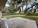 Spacious backyard featuring a wooden deck, green grass, and large trees providing ample shade at 4110 Longhorn Dr, Sarasota, FL 34233