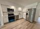 Bright kitchen featuring stainless steel appliances, white cabinetry, and new floors at 4110 Longhorn Dr, Sarasota, FL 34233