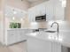Renovated kitchen with white cabinets, countertops, stainless appliances, and stylish pendant lighting at 4472 Calle Serena, Sarasota, FL 34238