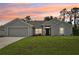 Charming single-story home with a well-manicured lawn and a two-car garage against a beautiful sunset sky at 4610 Clarke St, North Port, FL 34286