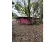 View of pink home exterior nestled among mature trees and greenery at 5011 Elfrida Ave, Sarasota, FL 34235