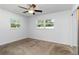 Bright bedroom with neutral carpet, ceiling fan, and two windows for natural light at 5200 Malaga Ave, Sarasota, FL 34235