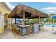 Outdoor bar with a thatched roof, ample seating, and a view of the pool, perfect for entertaining at 5368 Eliseo St, Sarasota, FL 34238