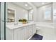Bathroom featuring tiled floors, white double vanity, framed mirror, white cabinets, and soaking tub at 5368 Eliseo St, Sarasota, FL 34238