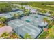 Aerial view of multiple tennis courts surrounded by lush trees and a view of a community lake at 5368 Eliseo St, Sarasota, FL 34238