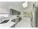 Bright kitchen featuring stainless steel appliances, gray cabinetry and sleek white marble flooring at 5508 83Rd E Ter, Sarasota, FL 34243