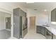 Modern kitchen with stainless steel refrigerator, white marble floors, and gray cabinets at 5508 83Rd E Ter, Sarasota, FL 34243
