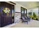 Inviting front porch with stone accents, a wreath-adorned door, and cozy seating area at 5644 Flagstone Trl, Palmetto, FL 34221