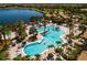 Aerial view of the community pool featuring tropical landscaping, a lake, and plenty of lounging areas at 6714 Alstead Cir, Bradenton, FL 34202