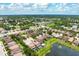 An aerial shot of a neighborhood showcases the properties and the community pool by a pond at 7020 Island Queen Ct, Sarasota, FL 34233