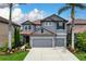 Charming two-story home featuring a gray stucco exterior, red tile roof, and meticulously landscaped front yard at 7020 Island Queen Ct, Sarasota, FL 34233