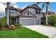 Charming two-story home featuring a gray stucco exterior, red tile roof, and meticulously landscaped front yard at 7020 Island Queen Ct, Sarasota, FL 34233