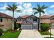 Charming two-story home featuring a gray stucco exterior, red tile roof, and meticulously landscaped front yard at 7020 Island Queen Ct, Sarasota, FL 34233