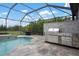 Outdoor kitchen on screened patio featuring a stainless steel grill, set in stone at 7020 Island Queen Ct, Sarasota, FL 34233
