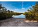 A sandy boat ramp leading into a serene body of water surrounded by lush greenery and a blue sky at 715 Fontana Ln, Bradenton, FL 34209