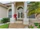 Close-up of the front entrance with decorative columns, a double glass door, and manicured flowerbeds at 7327 38Th Court East, Sarasota, FL 34243