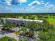 Aerial shot shows a condo surrounded by lush greenery, trees, and ample parking at 7461 W Country Club N Dr # 203, Sarasota, FL 34243