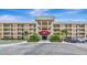 Front view of a multi-story building featuring a covered entrance, balconies, and well-manicured landscaping at 7461 W Country Club N Dr # 203, Sarasota, FL 34243