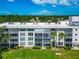 Detailed exterior of a multi-story condominium with screened balconies, lush landscaping, and scenic surroundings at 7461 W Country Club N Dr # 203, Sarasota, FL 34243
