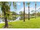 Scenic backyard featuring lush green grass, palm trees, and a tranquil pond with reflections at 7926 Woodpointe Ct # 29, Sarasota, FL 34238