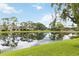 Scenic view of the community pond reflecting the surrounding lush greenery and clear blue sky at 7926 Woodpointe Ct # 29, Sarasota, FL 34238