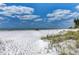 Serene beach scene with white sand, clear water, and beach chairs under a colorful umbrella at 101 Whispering Sands Dr # 307, Sarasota, FL 34242