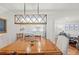 Bright dining room features wood table and a stylish light fixture, seamlessly connecting to the modern, all-white kitchen at 101 Whispering Sands Dr # 307, Sarasota, FL 34242