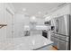 All-white kitchen features stainless appliances, bright lighting, and modern backsplash for a sleek, contemporary feel at 101 Whispering Sands Dr # 307, Sarasota, FL 34242