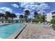 Inviting community pool surrounded by palm trees, lounge chairs, and beautiful landscaping at 101 Whispering Sands Dr # 307, Sarasota, FL 34242