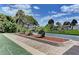 Outdoor shuffleboard court with landscaping, surrounded by tropical trees and green grass at 101 Whispering Sands Dr # 307, Sarasota, FL 34242