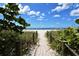 Inviting beach access path leading to the sunny sands, framed by greenery and a beautiful blue sky at 105 Inlets Blvd # 105, Nokomis, FL 34275