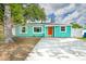 Charming single-story home with a bright teal exterior and orange door, surrounded by mature trees and a concrete driveway at 115 41St Ne Ave, St Petersburg, FL 33703