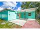 Rear view of home showcasing teal exterior, covered patio, and additional outdoor space at 115 41St Ne Ave, St Petersburg, FL 33703