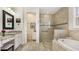 Elegant bathroom featuring a soaking tub, glass-enclosed shower, and dual vanities with stone countertops at 11625 Parrotfish St, Venice, FL 34292