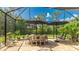 Screened-in brick patio with a wood table and chairs, along with two large umbrellas and lush landscaping at 11625 Parrotfish St, Venice, FL 34292