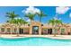 View of the community pool with a clubhouse, chairs, and lots of palm trees at 11625 Parrotfish St, Venice, FL 34292
