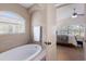 Relaxing bathroom showcasing a soaking tub, arched window, and a partial view into the bedroom at 12031 Longview Lake Cir, Lakewood Ranch, FL 34211