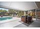 Outdoor covered patio with a dining table near the pool and lounging chairs surrounded by landscaped yard at 1207 71St Nw St, Bradenton, FL 34209