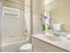 Bright bathroom featuring a tub-shower combo and a modern vanity with decorative orchids at 12331 Halfmoon Lake Ter, Bradenton, FL 34211